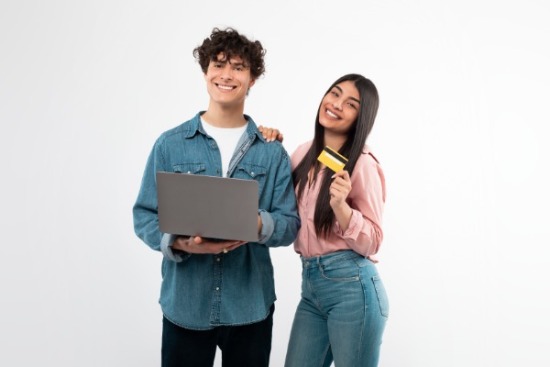 Teen boy and girl with debit card and computer