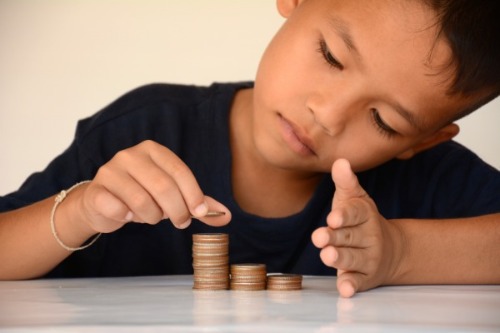 little boy counting stacks of coins
