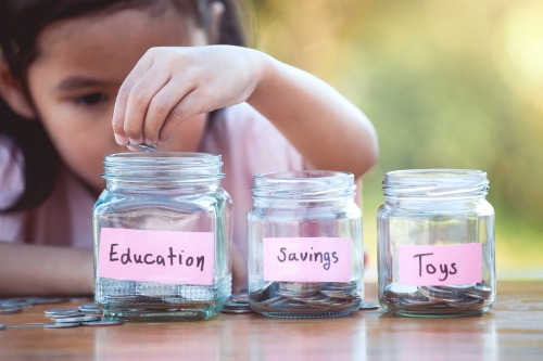 little girl putting money in jars