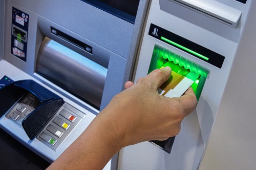 Person inserting debit card into an ATM