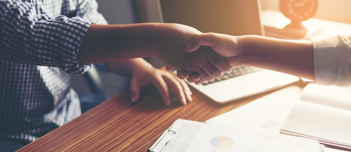 Lender and client shaking hands at desk