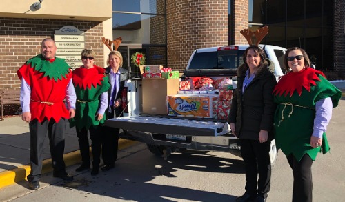 Group dressed as elves and reindeer in front of truck filled with donation items