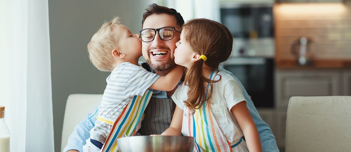 Two children kissing their father on the cheek