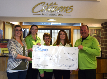 Group holding check and smiling for NUMAS Haus donation
