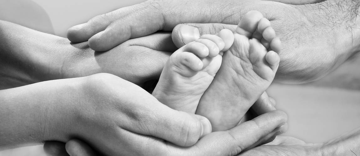 Mom and Dad hands wrapped around baby's feet
