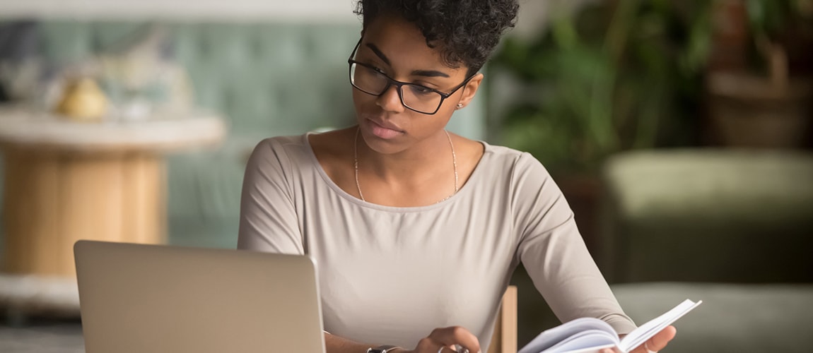 Woman using computer and reading a book