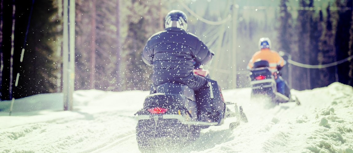Two snowmobilers riding on a trail