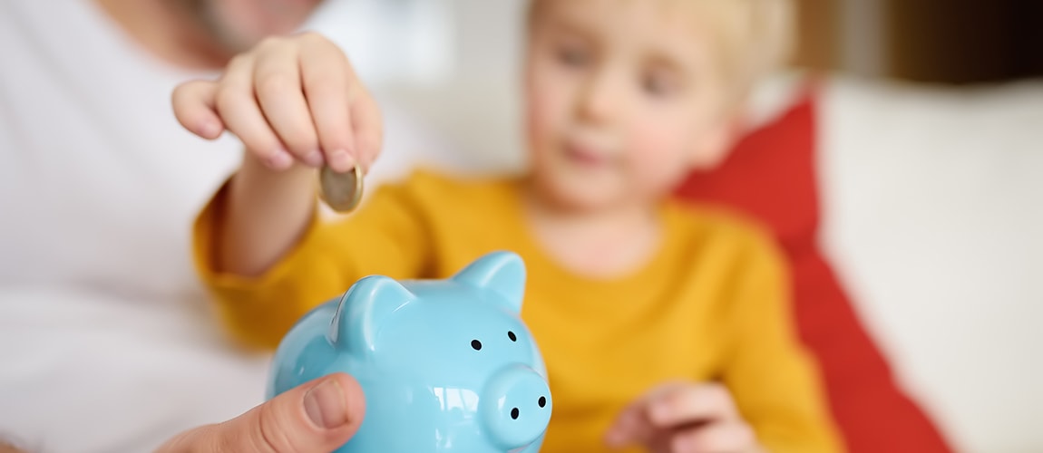 Young boy putting coin into his piggy bank