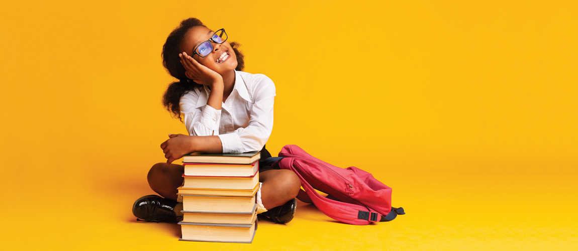 Little girl smiling with a pile of books