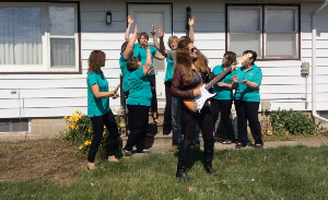 Group outside home dancing while woman plays guitar